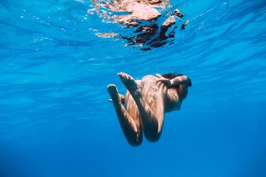 Su altında mavi okyanusta yüzen güzel çıplak kadın