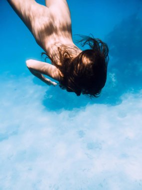 Su altında mavi okyanusta yüzen güzel çıplak kadın