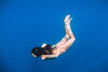 Su altında mavi okyanusta yüzen güzel çıplak kadın