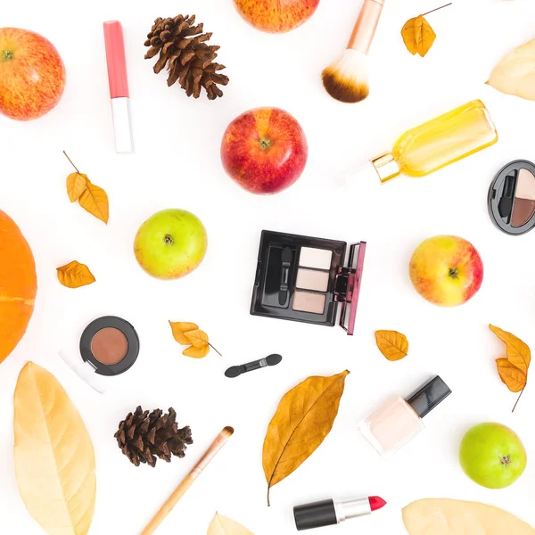 Thanksgiving background of fall leaves, feminine cosmetics and apples and pumpkin on white background. Flat lay, top view