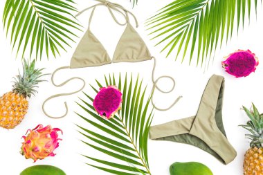 Cennet kavramı. Ananas, dragon meyve ve mango, beyaz arka plan üzerinde bikini mayo ile palmiye yaprakları. Düz yatıyordu, en iyi görünümü.