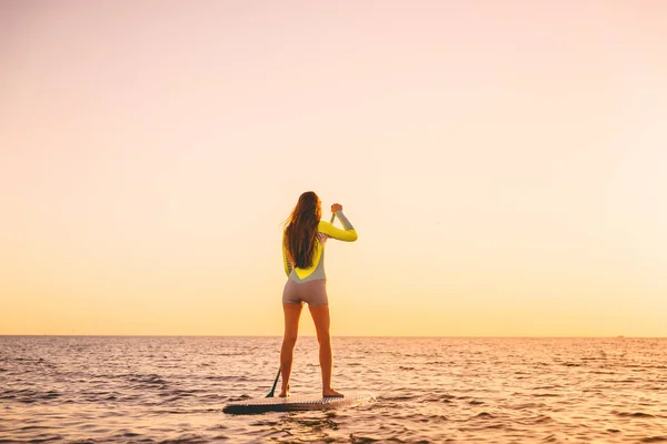 Wanita Muda Mengambang Berdiri Mendayung Papan Dengan Warna Matahari Terbenam — Stok Foto