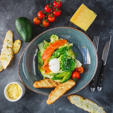 Sezar salatası yumurta, somon balığı, avokado, domates ve gri tablo üzerinde ızgara tost. Düz yatıyordu, en iyi görünümü