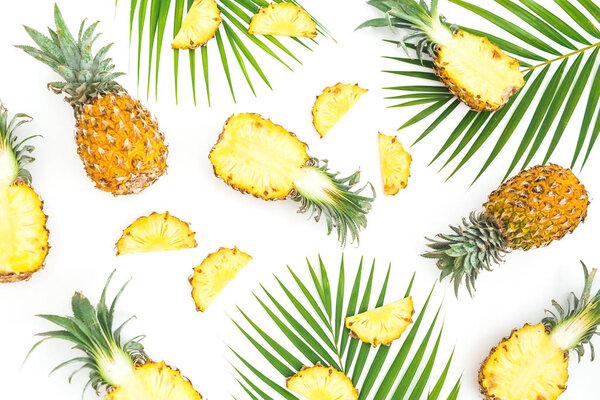 Тропический узор питания из фруктов ананаса с пальмовыми листьями на белом фоне. Плоский, вид сверху
.