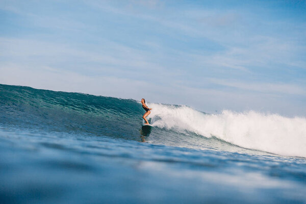 Professional surf girl at surfboard ride on barrel wave. Woman at ocean wave