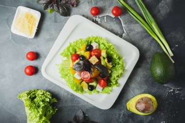 Taze sebze, peynir, zeytin ve gri masada fesleğen salata. Lezzetli yemekler arka plan. Düz yatıyordu