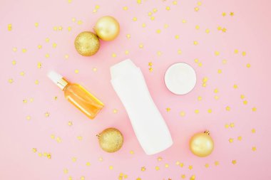 Topları dekorasyon ve altın konfeti şampuan şişesi üzerinde pembe bir arka plan ile. Düz yatıyordu, en iyi görünüm. Güzellik tatil kavramı.