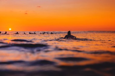 Sörfçü hattı üzerinde ve sörfçü kadın sıcak gün batımında. Okyanusta Sörf