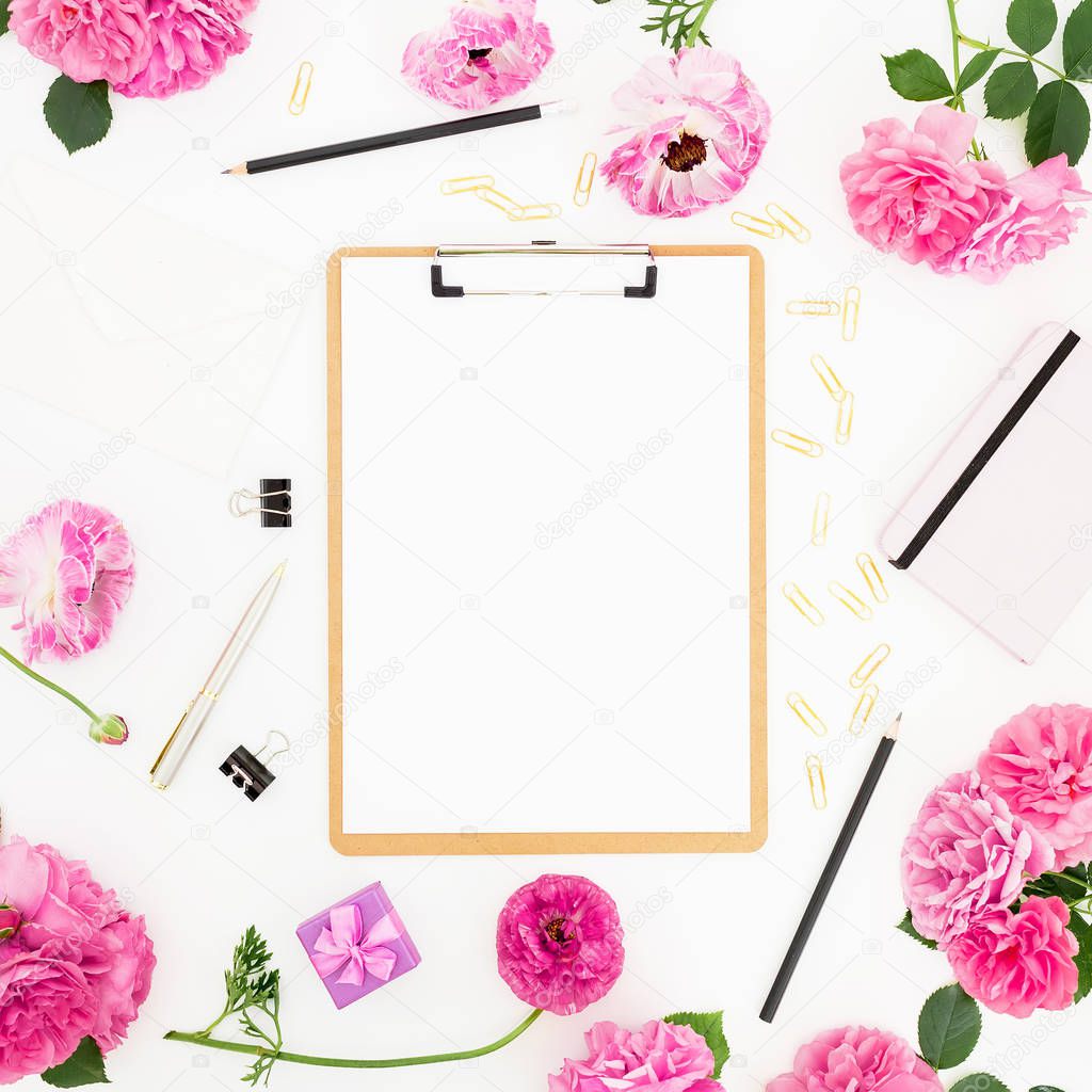 Work place with clipboard, pastel flowers and accessories on white background. Flat lay, top view. Blogger of freelancer concept