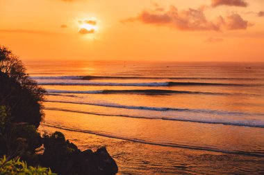 Okyanus ve ideal dalgalar ile parlak sıcak günbatımı için dalga köpüğü