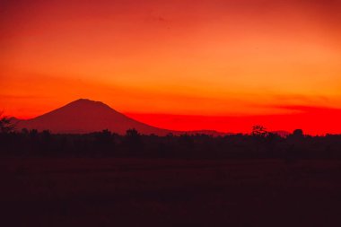 Bright colorful sunrise with silhouette of volcano in Bali clipart