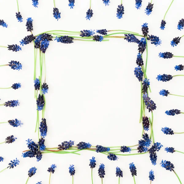 Floral frame with blue flowers and pink hyacinth flower on white background. Flat lay, top view.