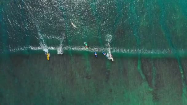 Tropický oceán s tyrkysovou vodou a surfaři na vlně. Letecký pohled