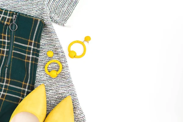 Female fashion cloth and accessories. Yellow shoes, earrings, sweater and pants on white background. Flat lay, top view.