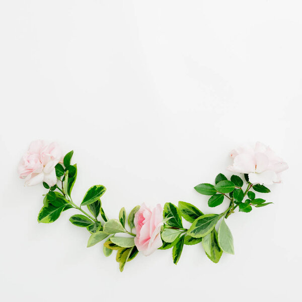 Floral composition of pastel pink roses and green leaves on white background. Flat lay, top view. Spring time.