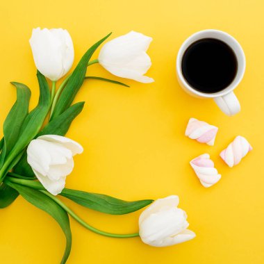 Çerçeve ile bir fincan kahve ve hatmi sarı zemin üzerine beyaz çiçek yaptı. Çiçek kavramı. Düz yatıyordu, en iyi görünümü.