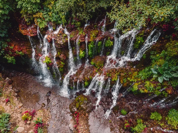 Amazing waterfall with clear water and red stones in tropical forest. Bali, Indonesia. Aerial view