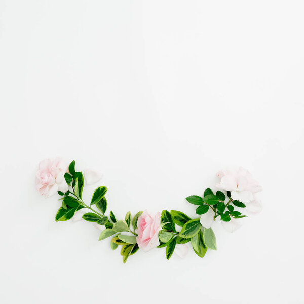 Floral composition of roses and green leaves on white background. Flat lay, top view.