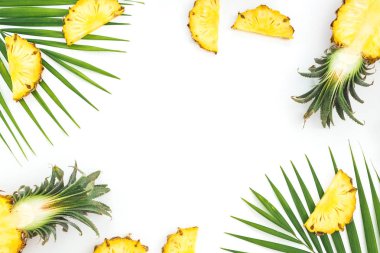 Beyaz arka plan üzerinde izole dilimlenmiş ananas ve palmiye yaprakları çerçevesinde. Düz yatıyordu, en iyi görünüm. Tropikal kavramı.