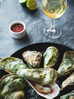 Beyaz şarap ve limes karanlık tablo üzerinde istiridye ve deniz ürünleri