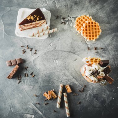 Gıda çerçevesinde sos, krema, pasta ve kurabiye damlama ile çikolatalı milkshake. Düz yatıyordu. Üstten görünüm