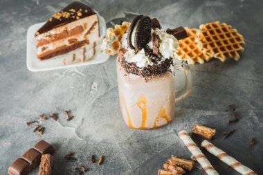 Sos, krema, kurabiye ve kek karanlık tablo üzerine damlama ile çikolatalı milkshake
