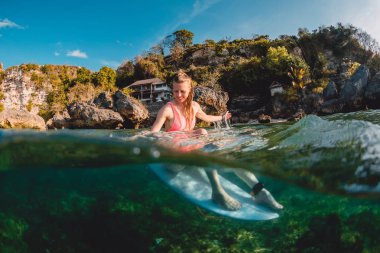Surfboard ile çekici sörfçü kız. Sörfçü oturup okyanusta panosu.