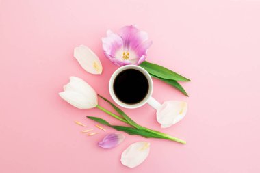 Çiçek, yaprakları ve pembe pastel arka plan üzerinde siyah kahve bir fincan ile kompozisyon. Düz yatıyordu, en iyi görünümü.