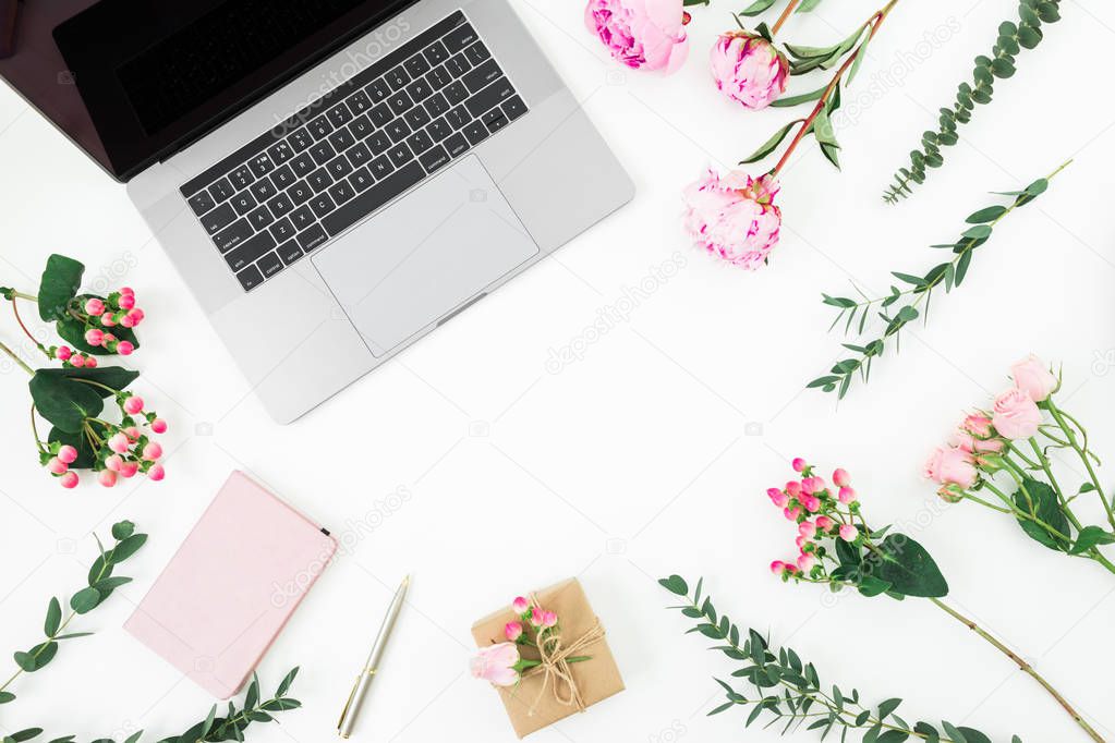 Frame with laptop, diary, pen, gift box and pink flowers and eucalyptus branches on white background. Flat lay. Top view. Feminine composition