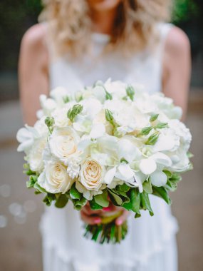 Gelin beyaz elbiseli bir buket gül çiçek ile tutar. Düğün günü ve tören