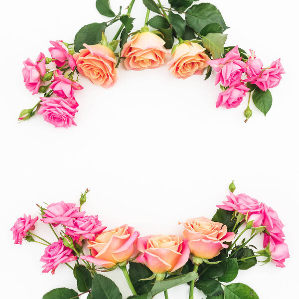 Floral frame of pink flowers and green leaves on white background. Flat lay, top view. Flower background
