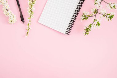Çerçeve bahar çiçekleri ve defter kalem üzerinde pembe bir arka plan ile. Düz yatıyordu, en iyi görünümü.