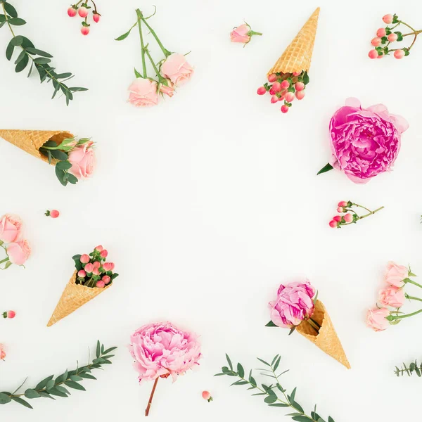 Floral frame of pink peonies, roses petals, eucalyptus and waffle cones on white background. Flat lay, top view