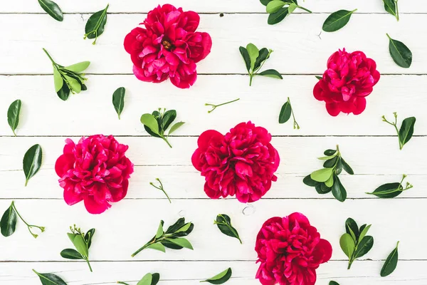 Floral pattern composition made of red peony flowers and leaves on white rustic background. Flat lay, top view.