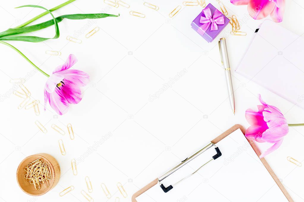 Work space concept with clipboard, notebook, pen, pink flowers and accessories on white background. Flat lay, top view. Copy space