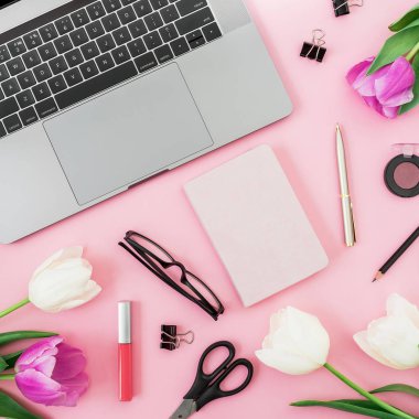 Dizüstü bilgisayar, süt, çiçek, Gözlük, kalem ve pembe bir arka plan için makaslar. Düz yatıyordu. Üstten görünüm. Serbest meslek veya iş kavramı