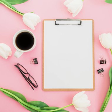 Bir fincan kahve, pano ve pembe bir arka plan üzerinde gözlük çiçeklerle. Kadınsı kavramı. Düz yatıyordu, en iyi görünümü.