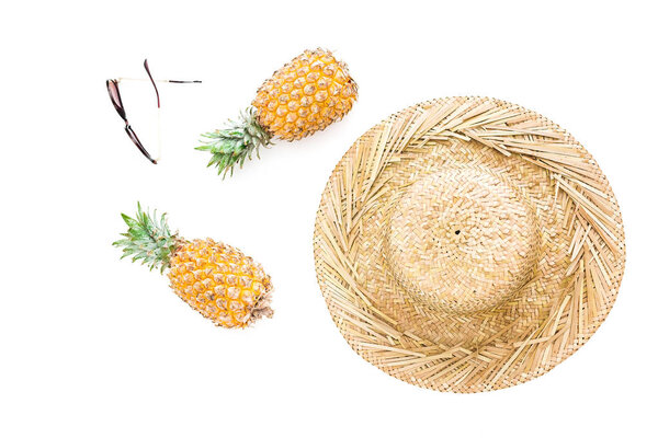 Holidays concept. Pineapple fruits, glasses and straw hat on white background. Flat lay, top view.