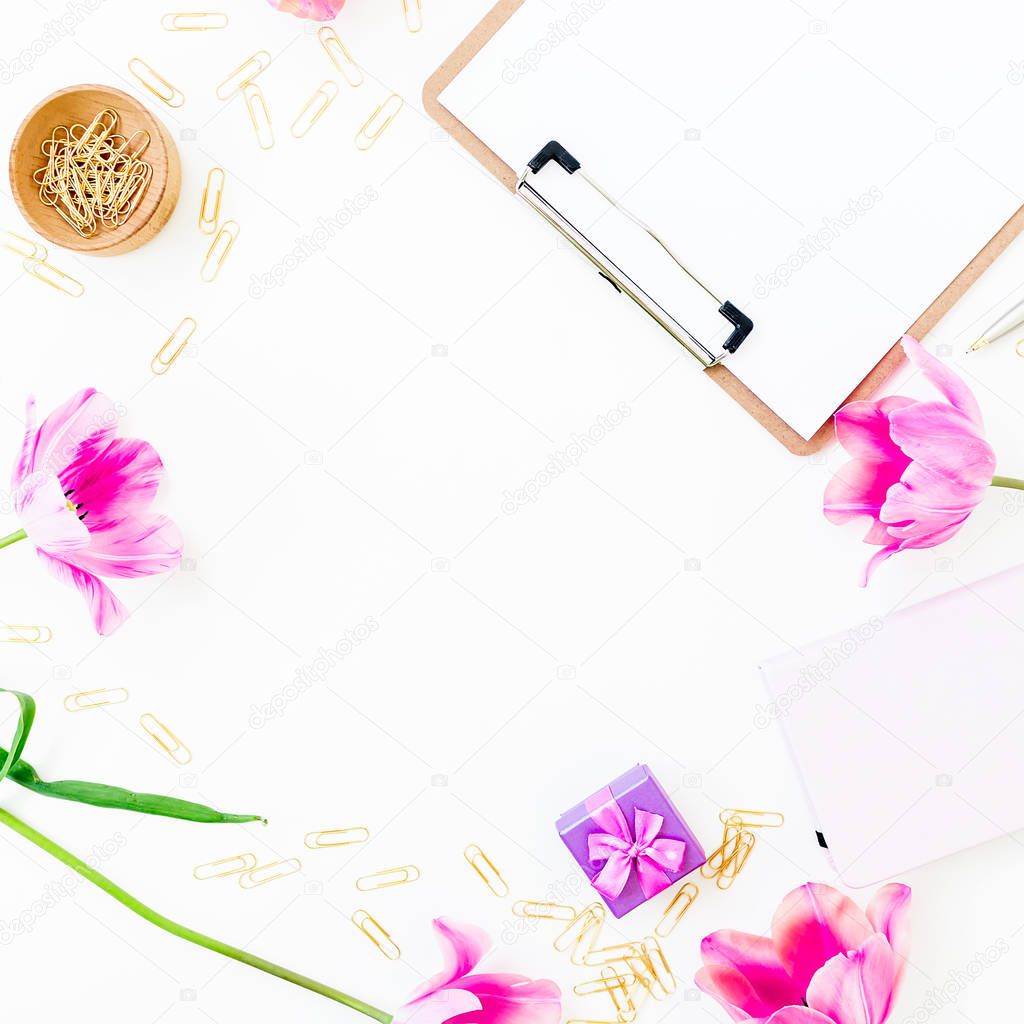 Work space frame with clipboard, notebook, pink flowers and accessories on white background. Flat lay, top view