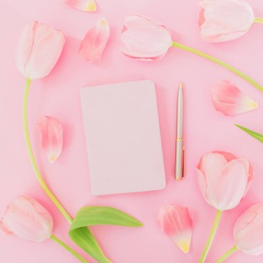Çiçek ve yaprakları ile defter ve kalem pembe bir arka plan üzerinde beyaz. Kadın blogger kavramı. Düz yatıyordu, en iyi görünümü.