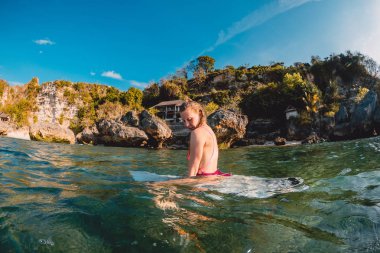 Surfboard ile çekici sörfçü kız. Sörfçü oturup okyanusta panosu.