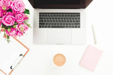 Ofis büro dizüstü, pembe gül buketi, kahve kupa, beyaz arka plan üzerinde pembe günlüğü ile. Düz yatıyordu. Üstten görünüm.