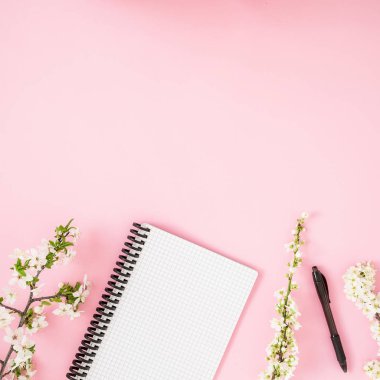 Beyaz bahar çiçekleri ve pembe bir arka plan üstünde defter ile çerçeve çiçek. Düz yatıyordu, en iyi görünüm. Bahar zaman kavramı.