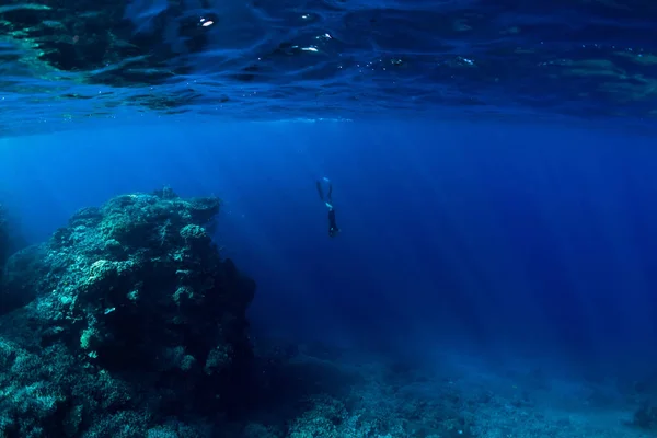 在水下有岩石和珊瑚的自由潜水员 — 图库照片
