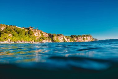 Mavi okyanus ve kayalıklarla Uluwatu, Bali ve günbatımı ışığı