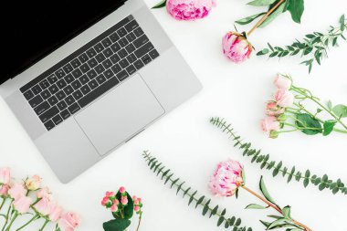 Beyaz arka plan üzerinde laptop ve pembe çiçekli Office çalışma alanı. Üstten görünüm. Düz yatıyordu.