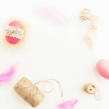 Paskalya gün. Pembe yumurta sicim, tüyler ve beyaz arka plan, üstten görünüm kasetlerde çerçeve yapılmış