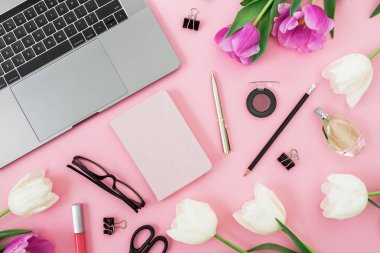 Ofis büro dizüstü bilgisayar, Lale çiçek, kozmetik, gözlük ve pembe bir arka plan üzerinde kalem. Düz yatıyordu. Üstten görünüm.