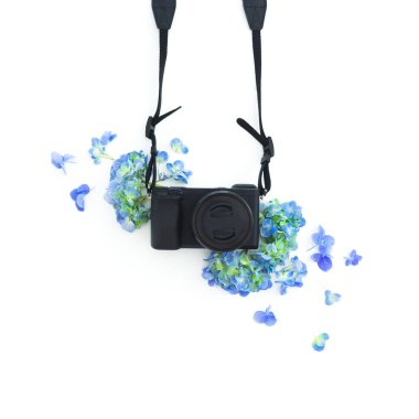 Fotoğraf makinesi ve beyaz zemin üzerine mavi çiçekler konseptiyle. Düz yatıyordu, en iyi görünümü.