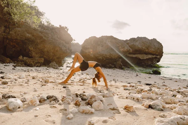 Genç kadın pratik yoga gündoğumu veya günbatımı Plajı'nda.